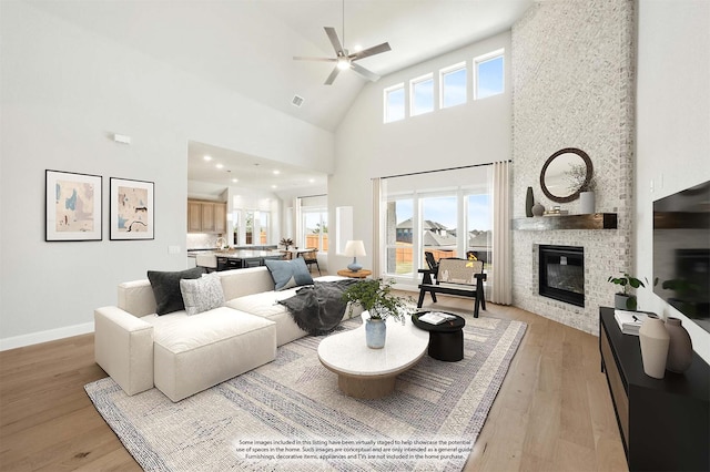 living room featuring ceiling fan, a fireplace, high vaulted ceiling, and light hardwood / wood-style flooring