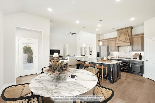 dining room with ceiling fan, light hardwood / wood-style floors, and lofted ceiling