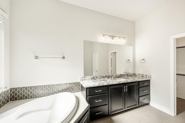 bathroom with tile patterned flooring, vanity, and tiled bath