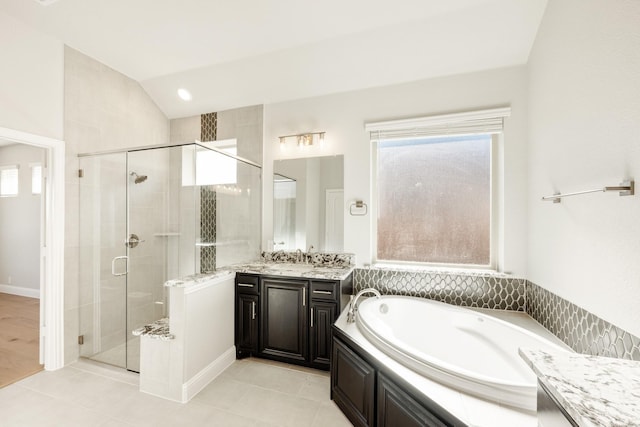 bathroom featuring tile patterned floors, vanity, a healthy amount of sunlight, and vaulted ceiling