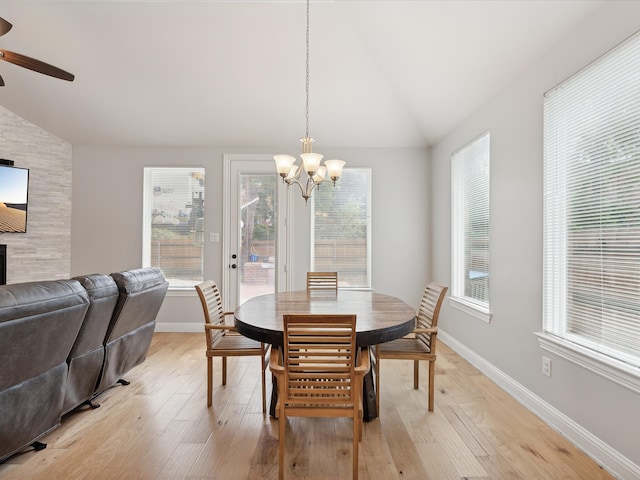 dining area with lofted ceiling, ceiling fan with notable chandelier, and light hardwood / wood-style floors