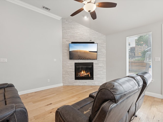 living room with a fireplace, light hardwood / wood-style flooring, lofted ceiling, ceiling fan, and ornamental molding