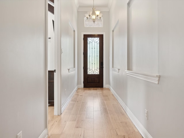 foyer featuring light wood-type flooring, a chandelier, and crown molding