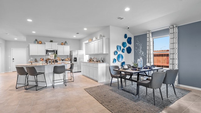 dining area featuring lofted ceiling and light tile patterned flooring