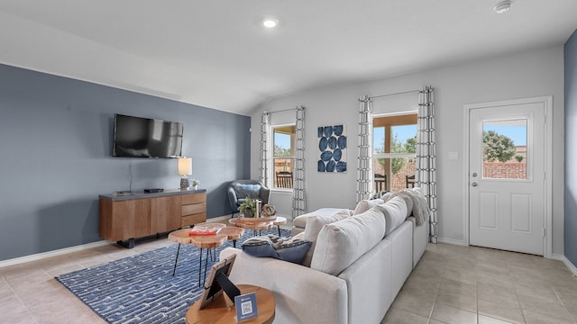 living room featuring a healthy amount of sunlight, vaulted ceiling, and light tile patterned floors