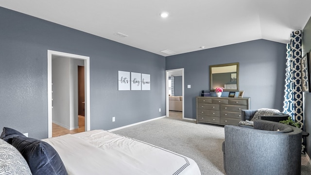 bedroom featuring lofted ceiling, light colored carpet, and connected bathroom