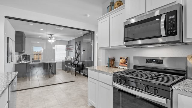 kitchen featuring ceiling fan, light stone countertops, appliances with stainless steel finishes, and white cabinets