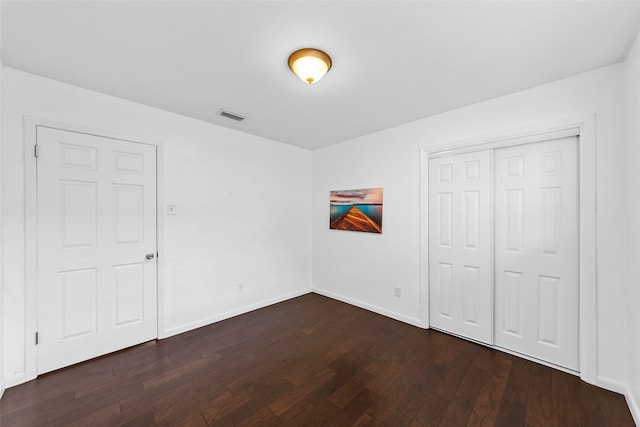 unfurnished bedroom with dark hardwood / wood-style flooring and a closet