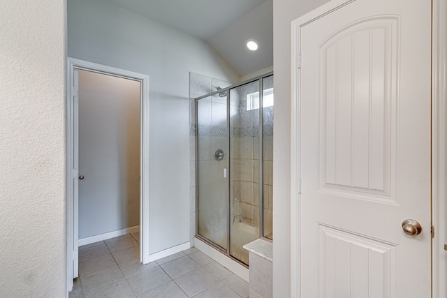 bathroom featuring lofted ceiling, a shower with shower door, and tile patterned floors