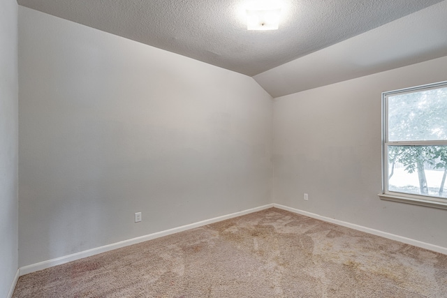 carpeted empty room with lofted ceiling and a textured ceiling