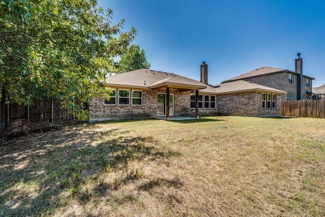 rear view of property with a lawn and a patio