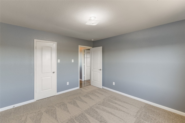 unfurnished bedroom featuring a textured ceiling, light carpet, and a closet