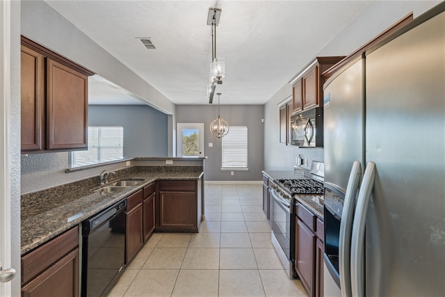 kitchen featuring light tile patterned flooring, track lighting, black appliances, dark stone countertops, and pendant lighting