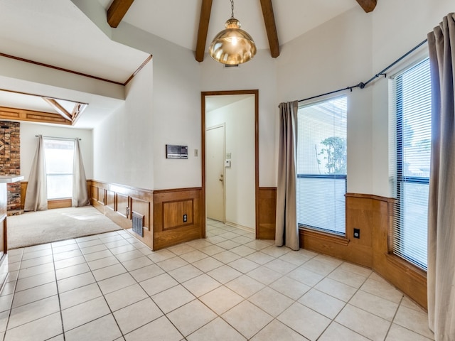 tiled spare room featuring wood walls, high vaulted ceiling, and beam ceiling