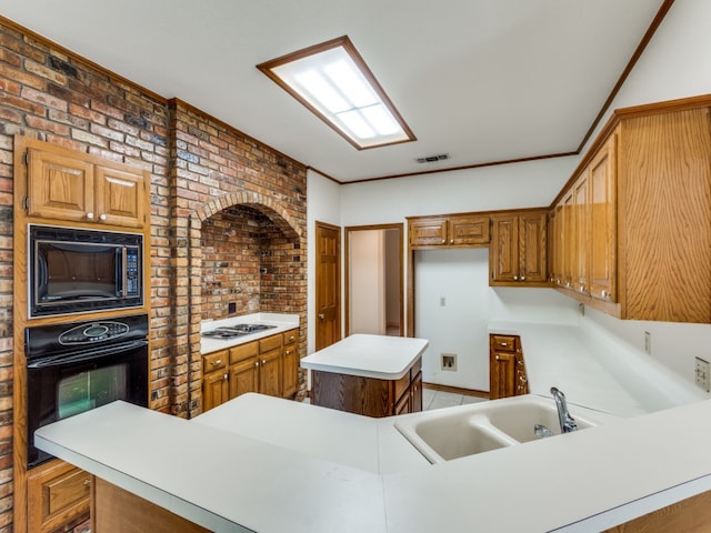 kitchen with black appliances, kitchen peninsula, sink, a kitchen island, and brick wall