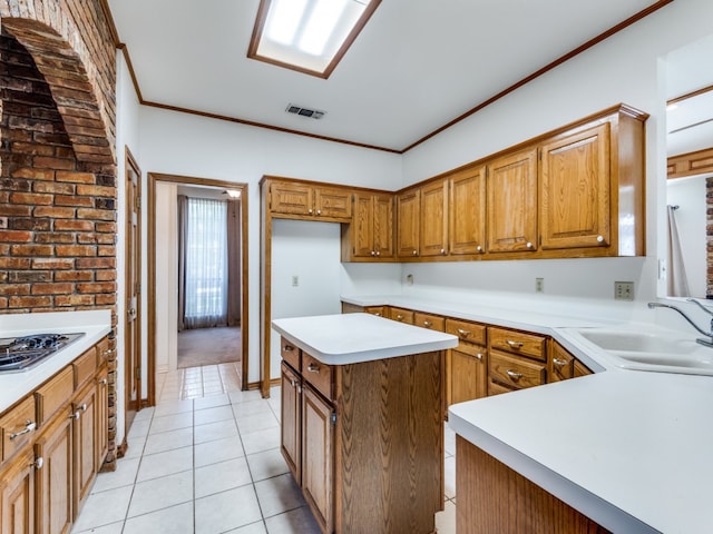 kitchen featuring ornamental molding, stainless steel gas cooktop, light tile patterned floors, a kitchen island, and sink