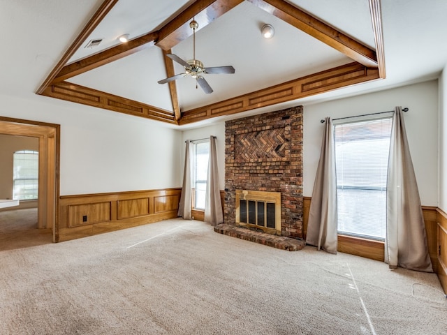 unfurnished living room with light colored carpet, ceiling fan, a brick fireplace, and lofted ceiling with beams