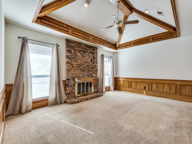 unfurnished living room with ceiling fan, vaulted ceiling with beams, light carpet, and a brick fireplace