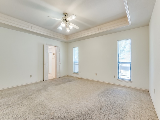 unfurnished room with ceiling fan, light colored carpet, and a raised ceiling