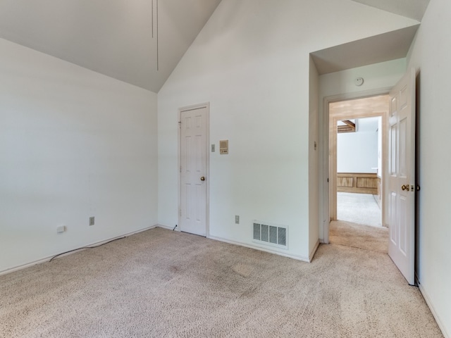 carpeted spare room with high vaulted ceiling