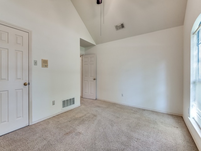 carpeted empty room with high vaulted ceiling