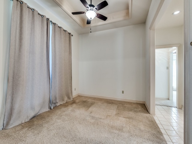 spare room featuring light carpet, a raised ceiling, and ceiling fan