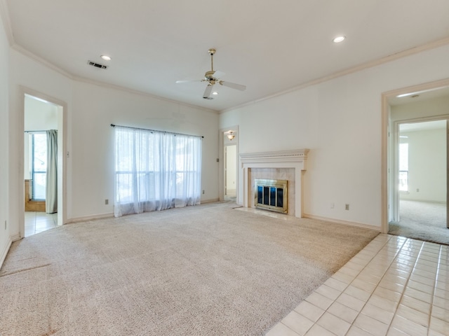 unfurnished living room with plenty of natural light, ceiling fan, light colored carpet, and a tile fireplace