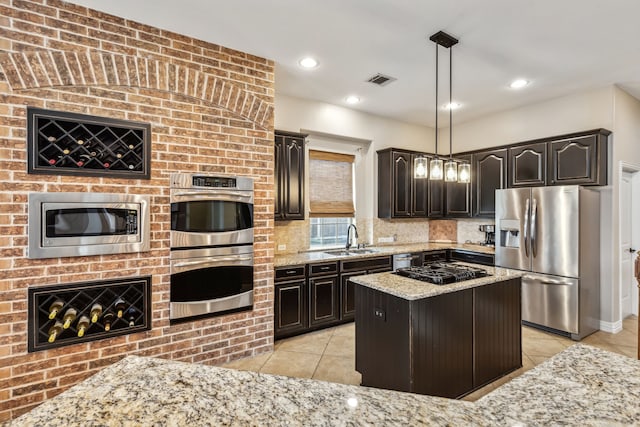 kitchen with light stone counters, a center island, decorative light fixtures, and appliances with stainless steel finishes