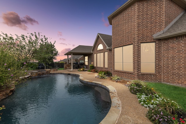 pool at dusk featuring a patio area