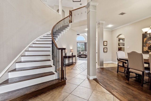 staircase with decorative columns, built in shelves, tile patterned floors, and crown molding