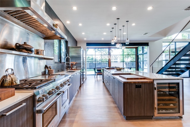 kitchen with appliances with stainless steel finishes, a healthy amount of sunlight, wine cooler, and light hardwood / wood-style floors