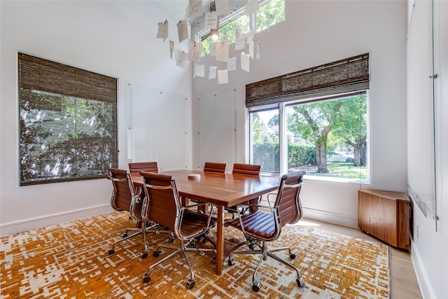 dining space featuring a towering ceiling and light hardwood / wood-style flooring