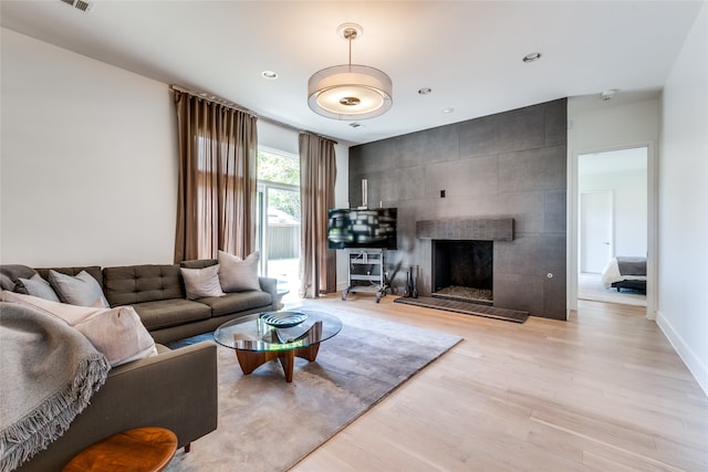 living room featuring a tiled fireplace and light hardwood / wood-style floors