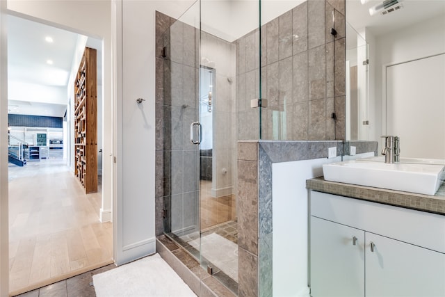 bathroom with hardwood / wood-style floors, a shower with door, and vanity