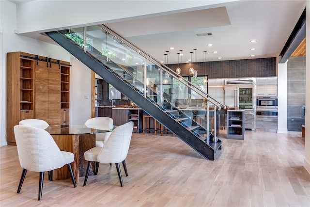 dining room featuring a barn door, indoor bar, and light wood-type flooring