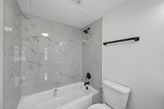 bathroom featuring a textured ceiling, toilet, and tiled shower / bath