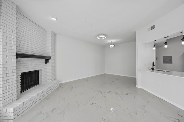 unfurnished living room featuring a brick fireplace, electric panel, and sink