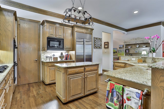 kitchen with a center island, light stone counters, sink, dark wood-type flooring, and built in appliances