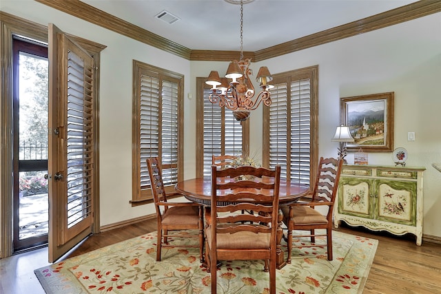 dining room featuring wood-type flooring, plenty of natural light, crown molding, and a notable chandelier