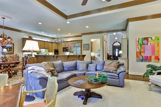 living room with ceiling fan with notable chandelier, light hardwood / wood-style floors, and ornamental molding