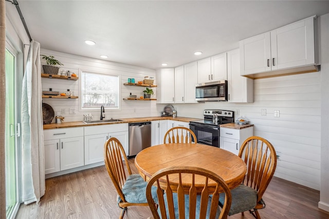 kitchen featuring wood counters, sink, appliances with stainless steel finishes, light hardwood / wood-style floors, and white cabinetry