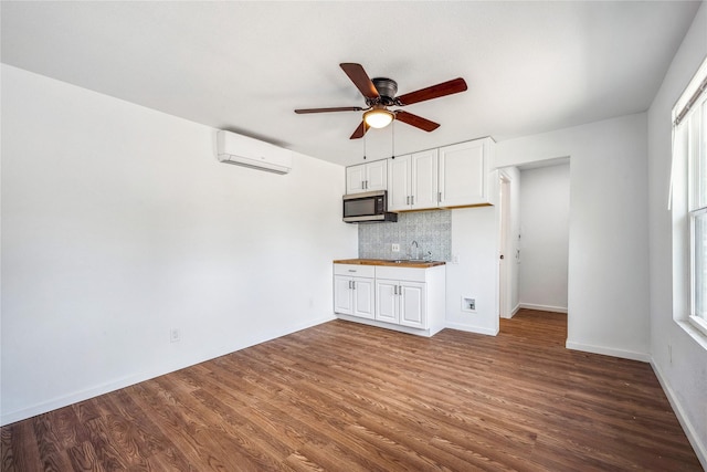 unfurnished living room featuring a healthy amount of sunlight, ceiling fan, dark wood-type flooring, and a wall mounted air conditioner