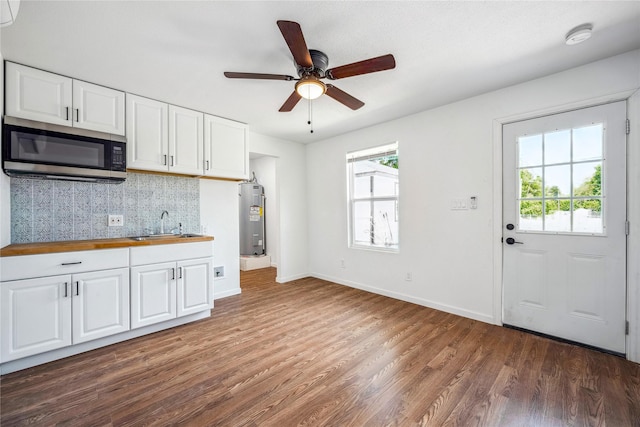 kitchen with white cabinetry, sink, ceiling fan, electric water heater, and dark hardwood / wood-style floors