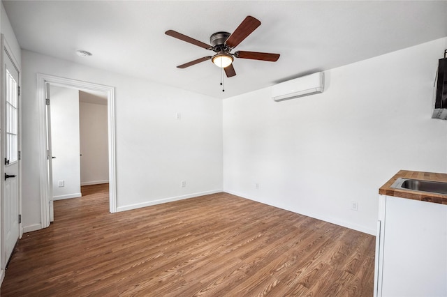 unfurnished living room featuring a wall mounted AC, ceiling fan, sink, and wood-type flooring