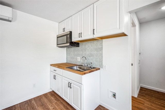 kitchen with wood counters, dark hardwood / wood-style floors, white cabinetry, and sink