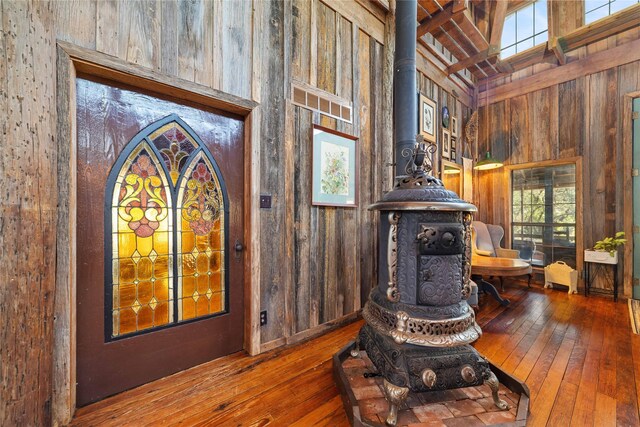 interior space with wood-type flooring, a wood stove, and wooden walls