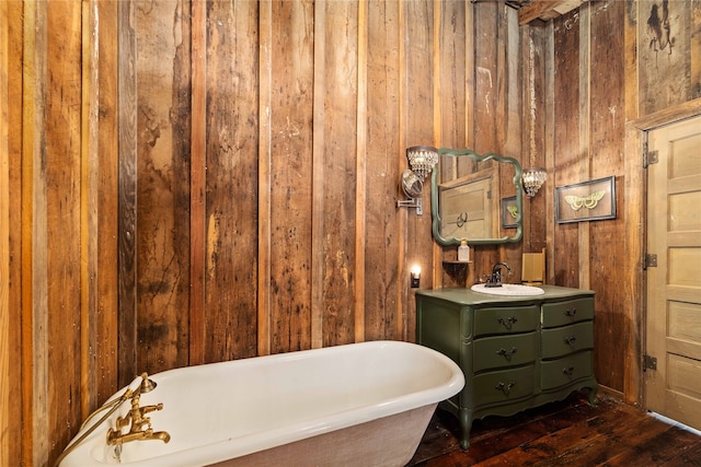 bathroom featuring vanity, wood-type flooring, wood walls, and a washtub