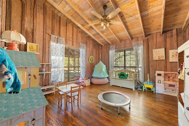 sitting room with wood walls, dark hardwood / wood-style floors, wood ceiling, lofted ceiling with beams, and ceiling fan