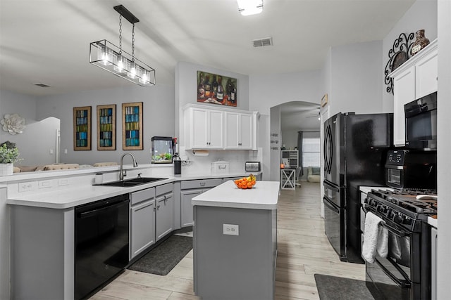 kitchen with light hardwood / wood-style flooring, black appliances, kitchen peninsula, a center island, and sink