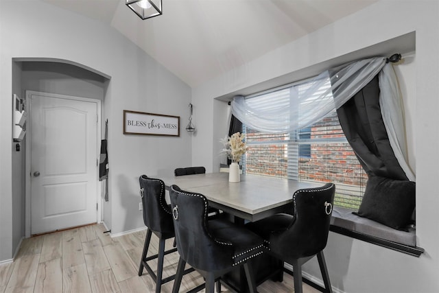 dining space featuring lofted ceiling and light hardwood / wood-style floors